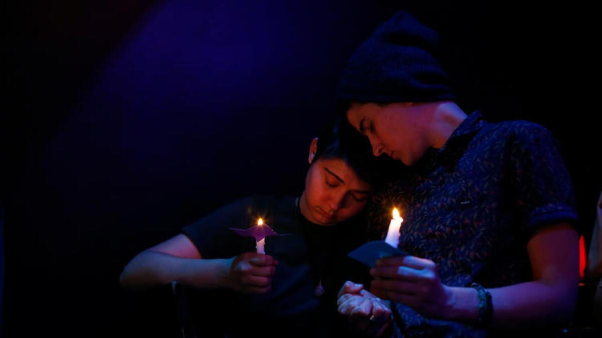 Sisters Sarah Bryant, left, and Katy Bryant, both from Irvine, listen as the names of the Orlando shooting victims are read during a vigil at the Velvet Lounge, a gay bar and club in Santa Ana.