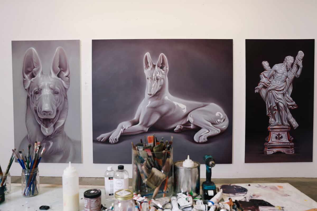 Three paintings of large porcelain animal and human figurines on the wall of an artist's studio 