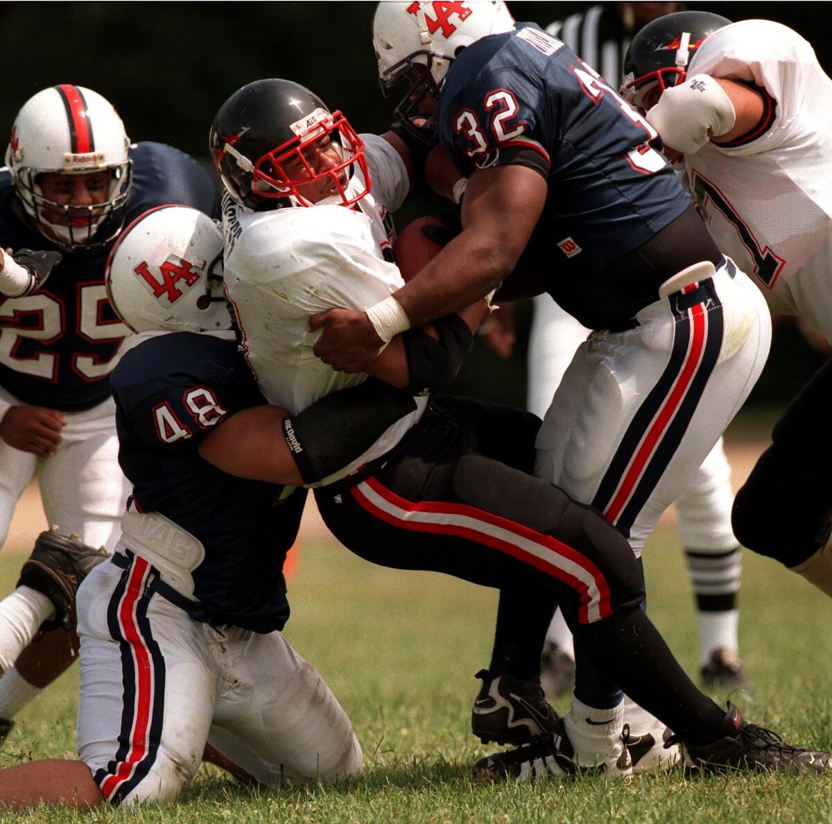 A runner is tackled by multiple defenders in a football game.