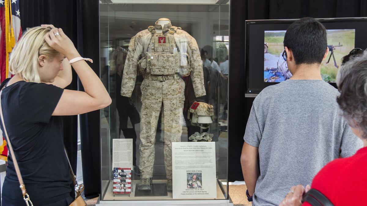 Visitors view the combat fatigues of former Navy SEAL Robert O'Neill, who was part of the mission that killed Osama bin Laden during a 2011 raid in Pakistan. O'Neill's uniform is on display at the Richard Nixon Presidential Library and Museum in Yorba Linda through July 31.