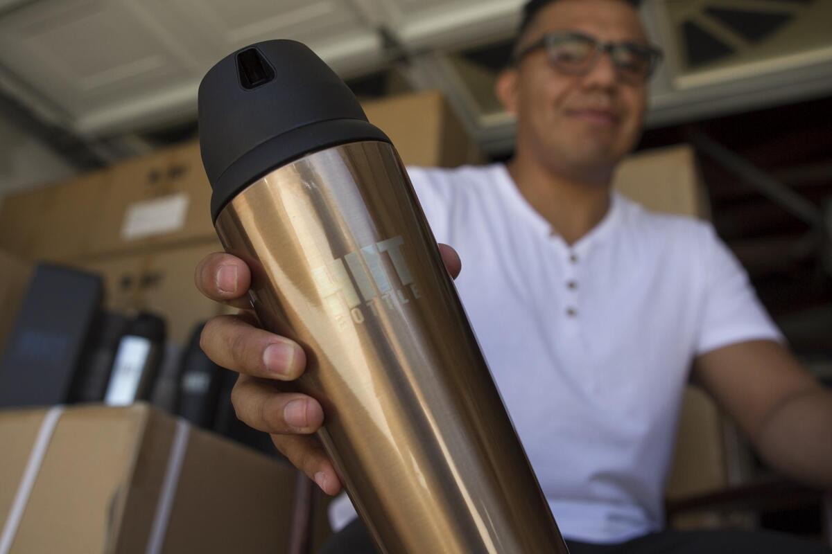 Christian Valencia holds a HIIT Bottle, a protein shaker product that he and his wife, Hannah, launched last year. The Valencias are Costa Mesa residents and Estancia High School alumni.