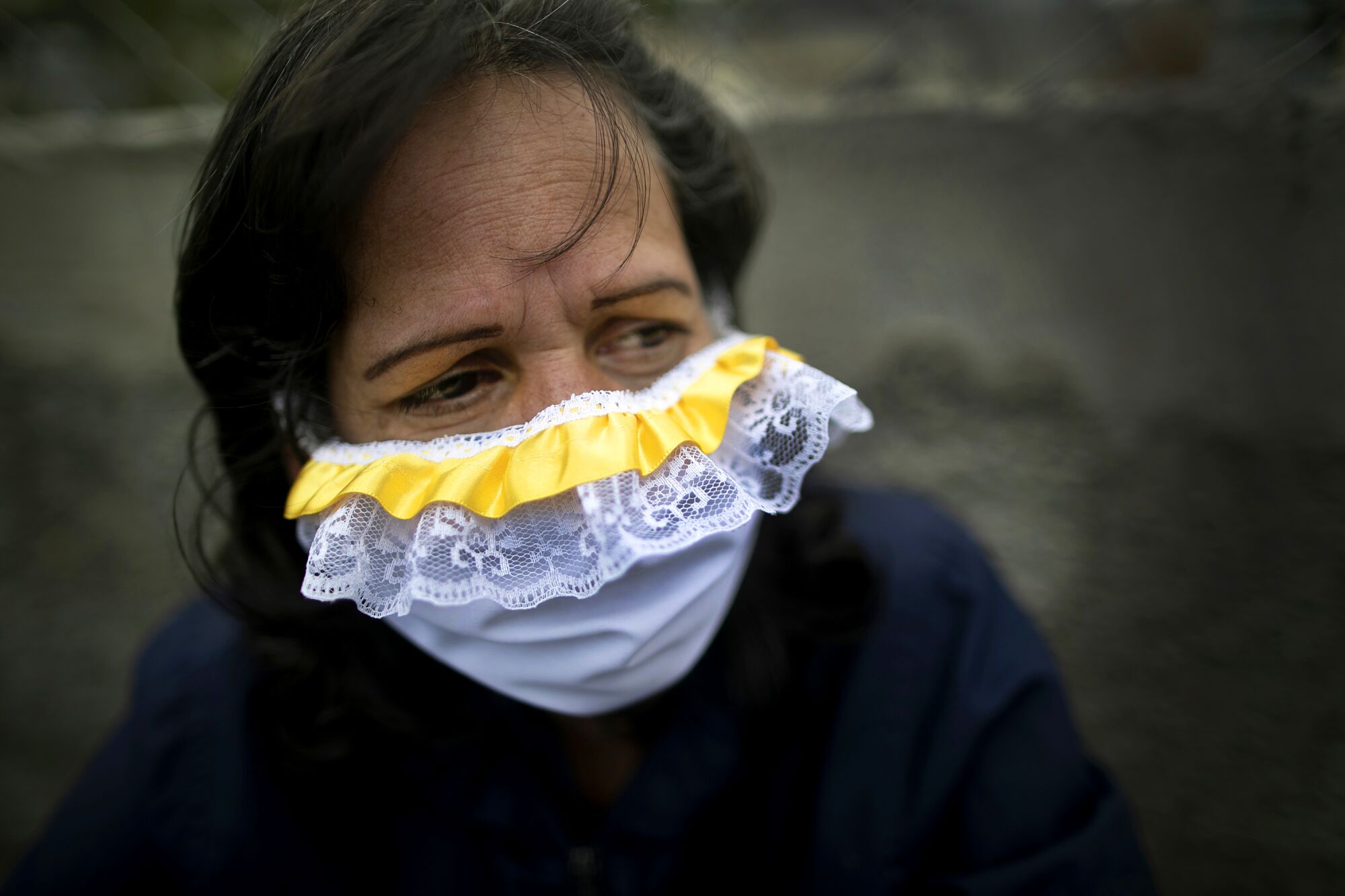 VENEZUELA: A woman wears a lacey homemade face mask as a precaution against the coronavirus as she waits in line to buy food in Caracas.