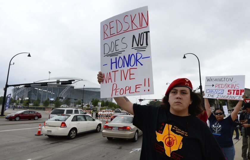 Demonstrators hold up signs in protest of the Washington Redskins name outside the AT&T; Stadium in Arlington, Texas.