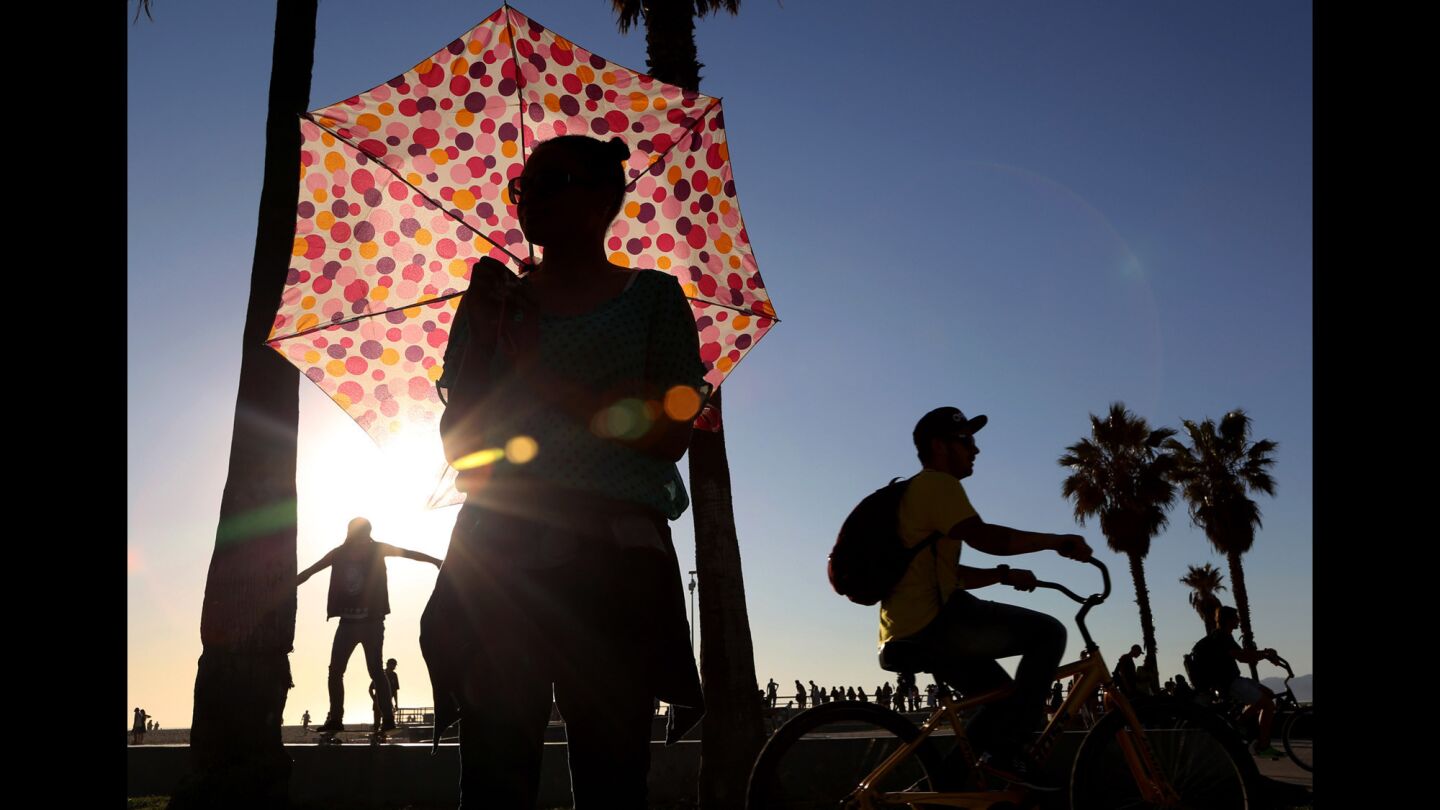 Ariel Rhone uses an umbrella for shade near the Venice boardwalk on Monday.