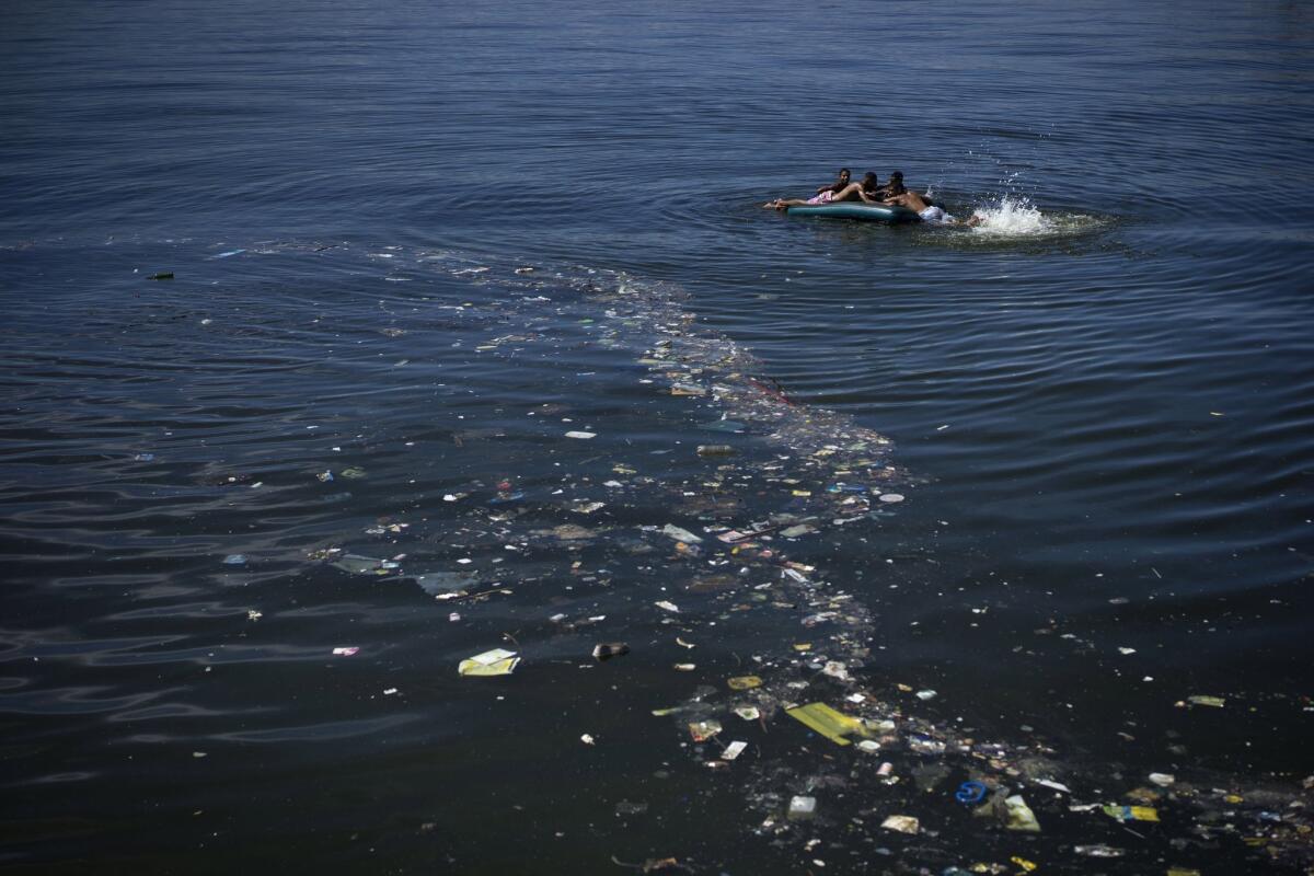Garbage floats alongside boys using an inflatable mattress on Oct. 31 in Guanabara Bay, which is slated to be used for events during the 2016 Summer Olympics in Rio de Janeiro.