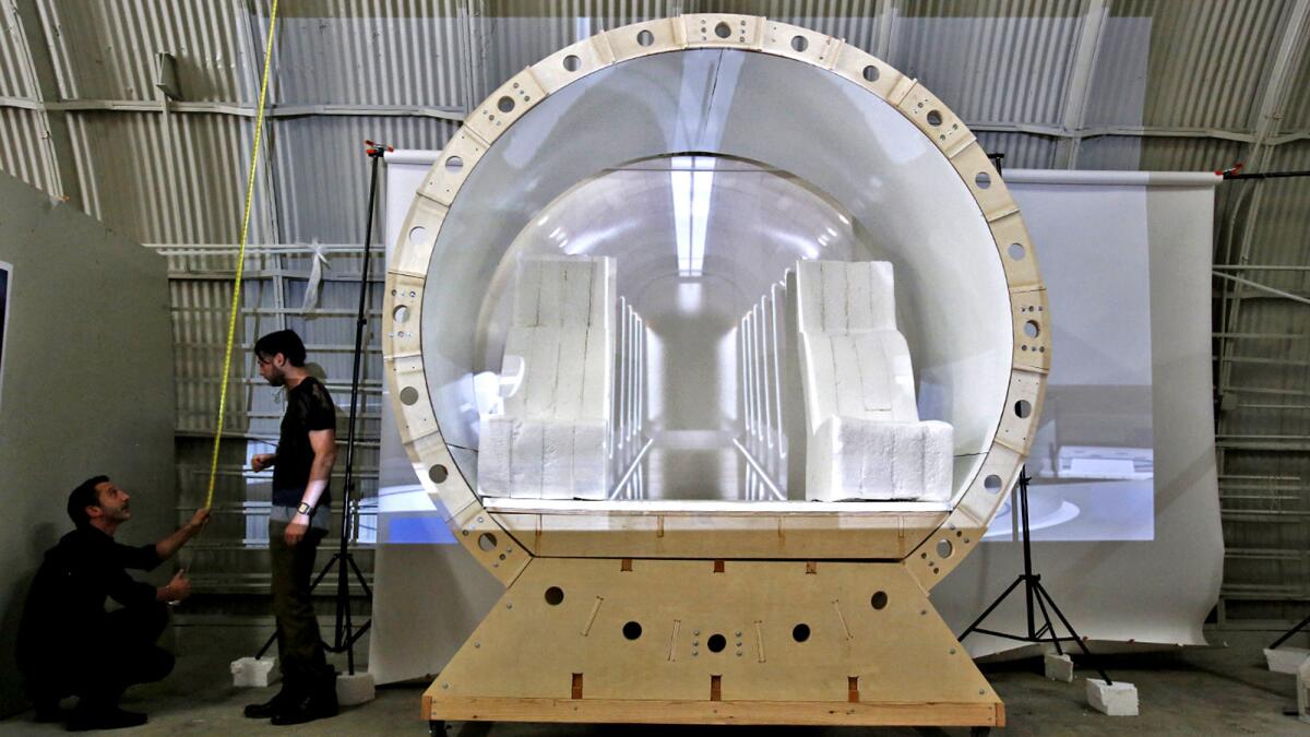 JJ Sansaone, left, and Andrew La Mendola take measurements for a backdrop of a Hyperloop capsule model. (Anne Cusack / Los Angeles Times)