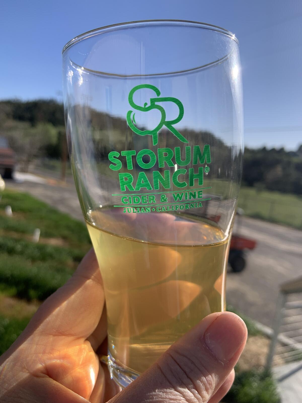 A close-up of a half glass of cider with a Storum Ranch label on the glass