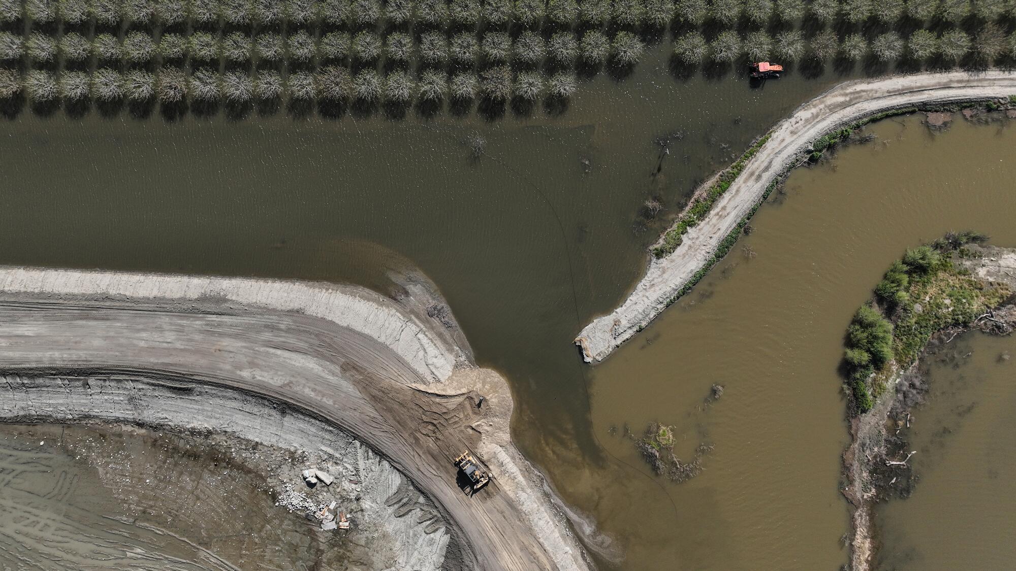 A skip loader works to repair a broken levee on the Tule River.