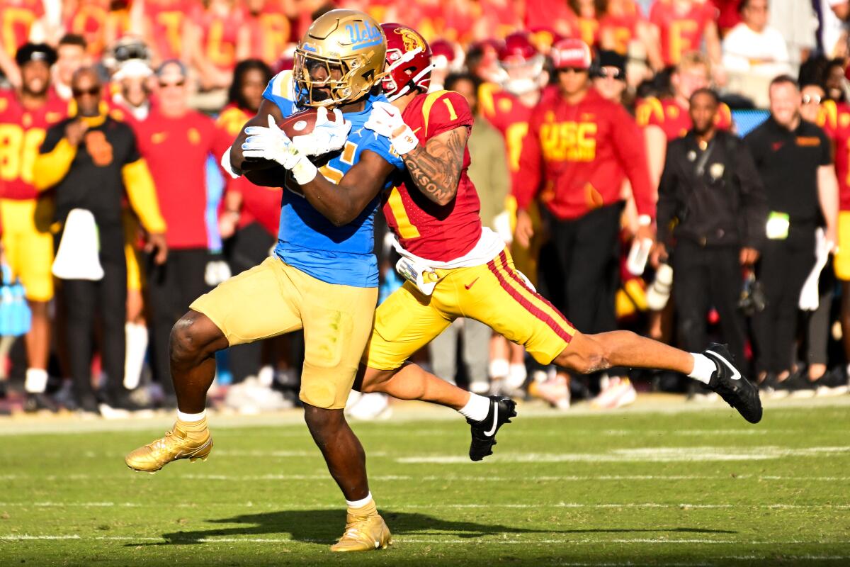 UCLA running back T.J. Harden runs with the ball as USC cornerback Domani Jackson tries to tackle him.