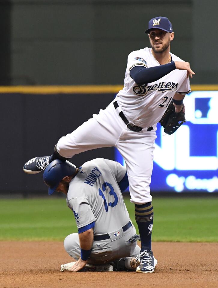 Dodgers Max Muncy is out at second base as Milwaukee Brewers second baseman Travis Shaw throw to first to complete the double play in the first inning.