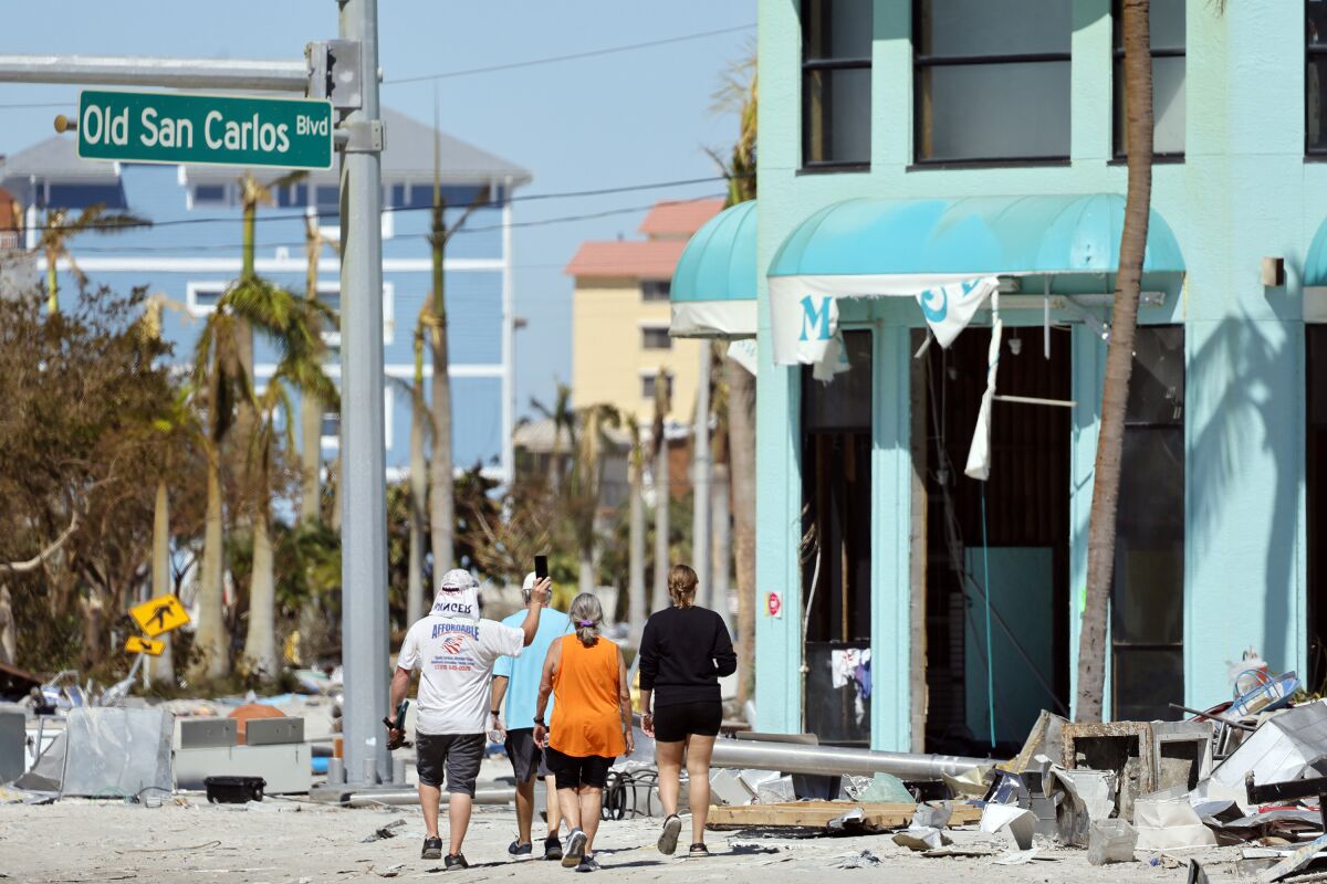Island residents walk around the downtown area on the island of Fort Myers Beach, Fla., Friday, Sept. 30, 2022. Hurricane Ian made landfall Wednesday, Sept. 28, 2022, as a Category 4 hurricane on the southwest coast of Florida. (Amy Beth Bennett/South Florida Sun-Sentinel via AP)