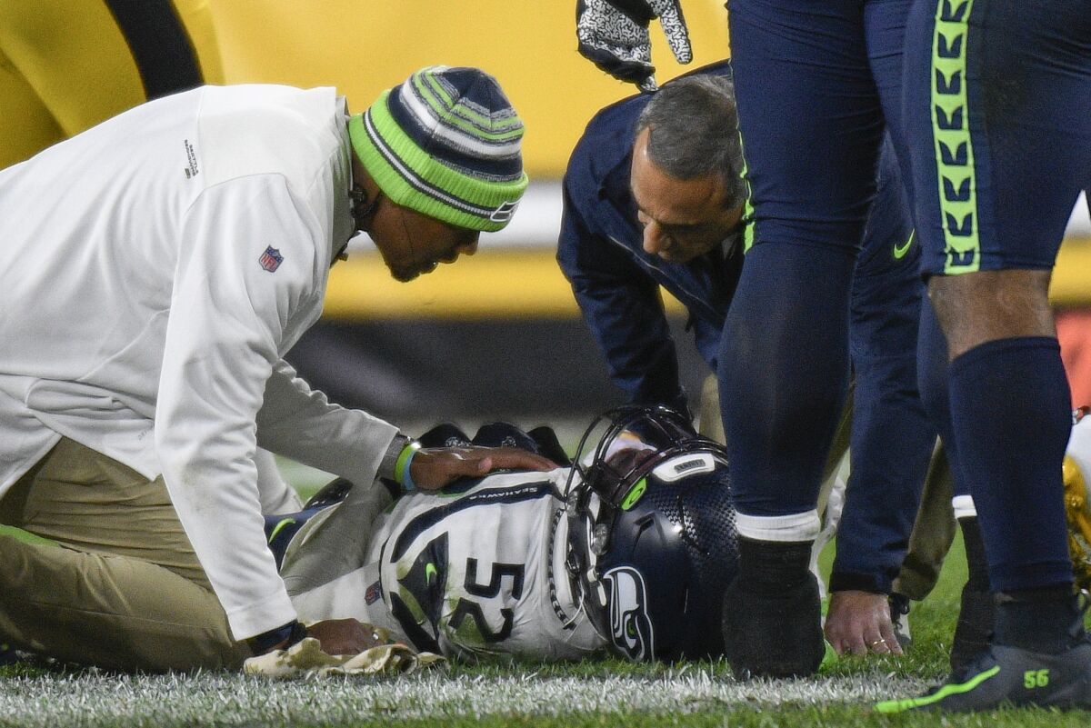 Seattle Seahawks defensive end Darrell Taylor (52) lays on the ground and is tended after being injured during the second half an NFL football game against the Pittsburgh Steelers, Sunday, Oct. 17, 2021, in Pittsburgh. (AP Photo/Don Wright)