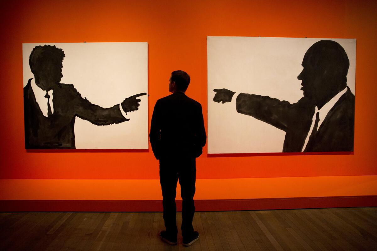 A gallery worker poses for photographs in front of Italian artist Sergio Lombardo's enamel paint on canvas works entitled "John F. Kennedy" and "Nikita Krusciov" at the press launch of "The EY Exhibition: The World Goes Pop" at the Tate Modern gallery in London, Monday, Sept. 14, 2015. The exhibition opens to public viewing from September 17 to January 24 and shows how artists around the world engaged with the spirit of pop art, with around 160 works from the 1960s and 70s on display. (AP Photo/Matt Dunham)