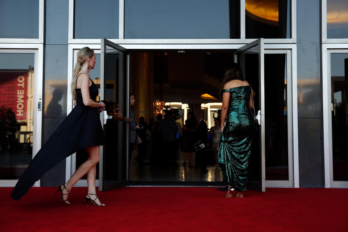 Women in gowns enter open theater doors.