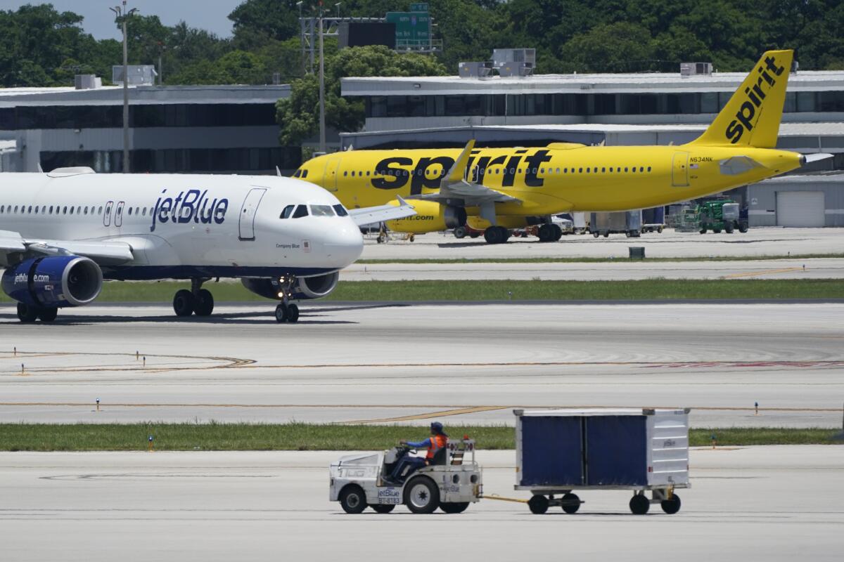 A JetBlue Airways airplane passes a Spirit Airlines plane at an airport.