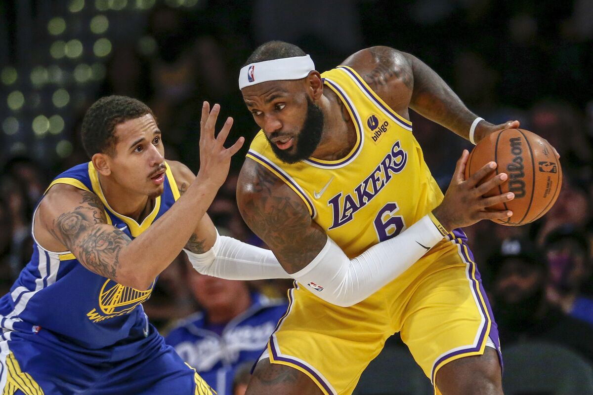 Los Angeles Lakers forward LeBron James, right, is defended by Golden State Warriors forward Juan Toscano-Anderson during the second half of a preseason NBA basketball game in Los Angeles, Tuesday, Oct. 12, 2021. (AP Photo/Ringo H.W. Chiu)