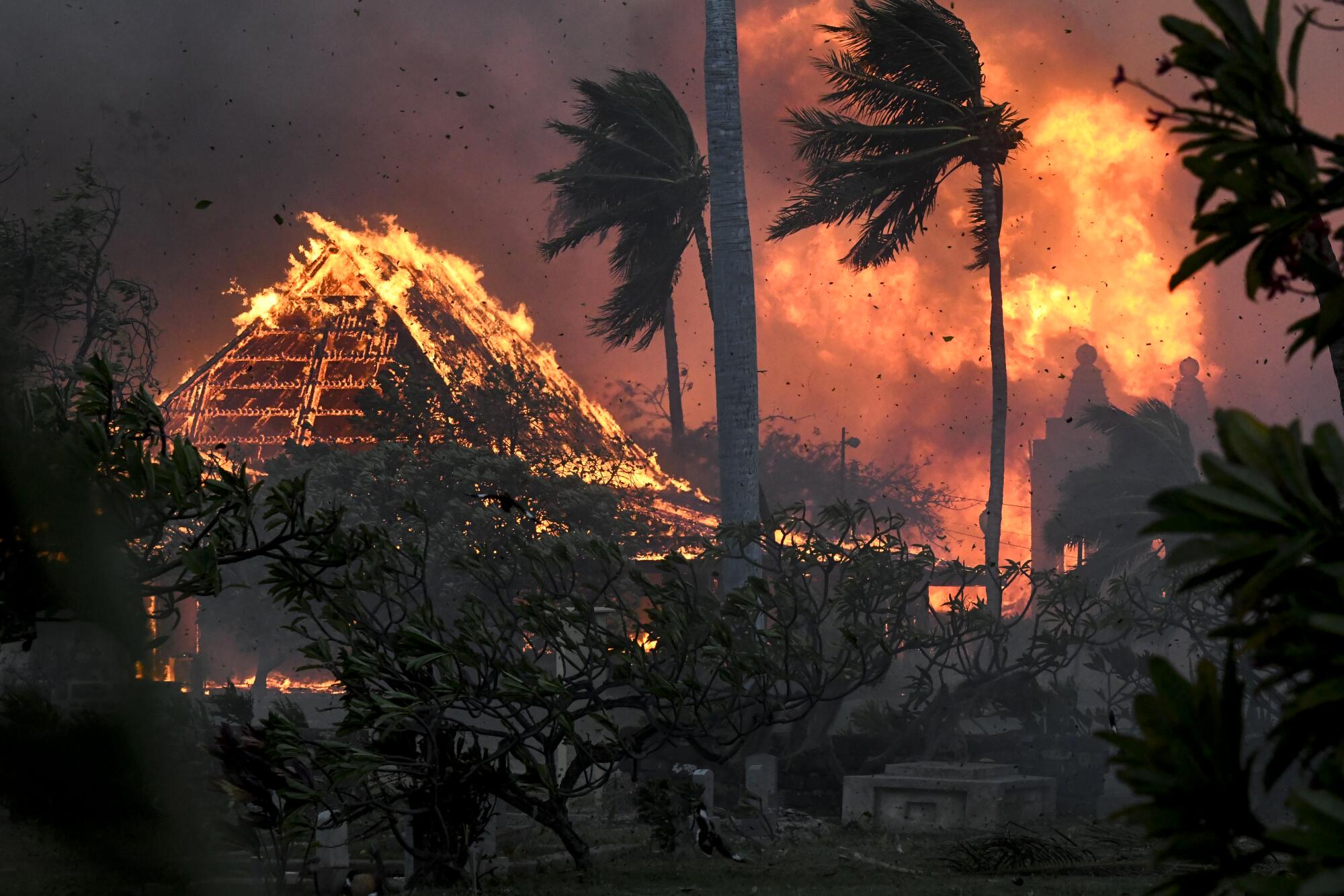 The hall of historic Waiola Church in Lahaina and nearby Lahaina Hongwanji Mission are engulfed in flames amid smoke.
