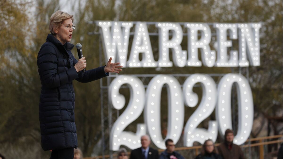 Sen. Elizabeth Warren speaks at a February 2019 event alongside a lighted "Warren 2020" sign. 