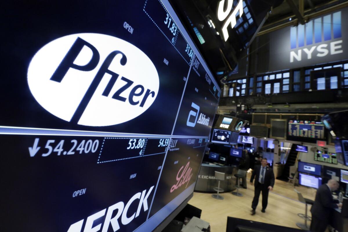 A monitor at the New York Stock Exchange shows the names and logos of Pfizer and other drugmakers.