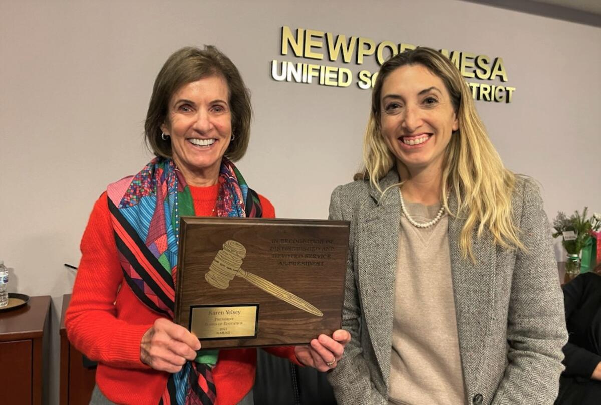Former NMUSD Board President Karen Yelsey, left, holds a commemorative plaque with newly appointed President Michelle Barto.