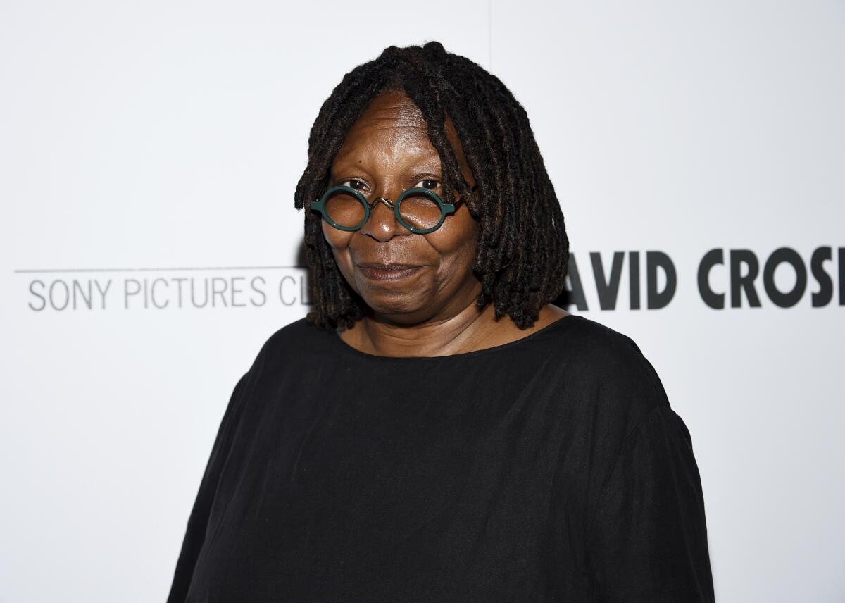 A woman posing in round glasses and a black shirt.