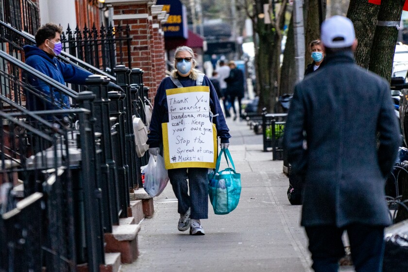 A pedestrian wears a sign thanking people for wearing face coverage in New York City on Wednesday.