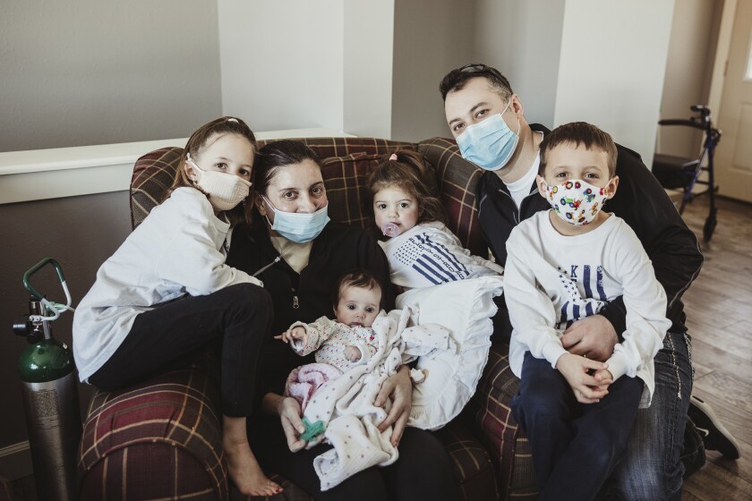 In this Jan. 27, 2021 photo provided by Taryn Marie Photography, the Townsend family poses for a photo in Poynette, Wis. the day mother Kelsey Townsend came home from the hospital, nearly three months after being admitted due to COVID-19. Townsend, second from left, gave birth to Lucy, in her arms, via C-section on Nov. 4 while in a medically induced coma. She spent 75 days on lung and life support. She finally met the daughter she delivered face to face on Jan. 27. (Taryn Ziegler/Taryn Marie Photography via AP)