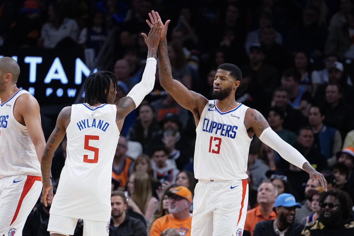 Clippers guard Bones Hyland, left, high-fives forward Paul George during a game last season.