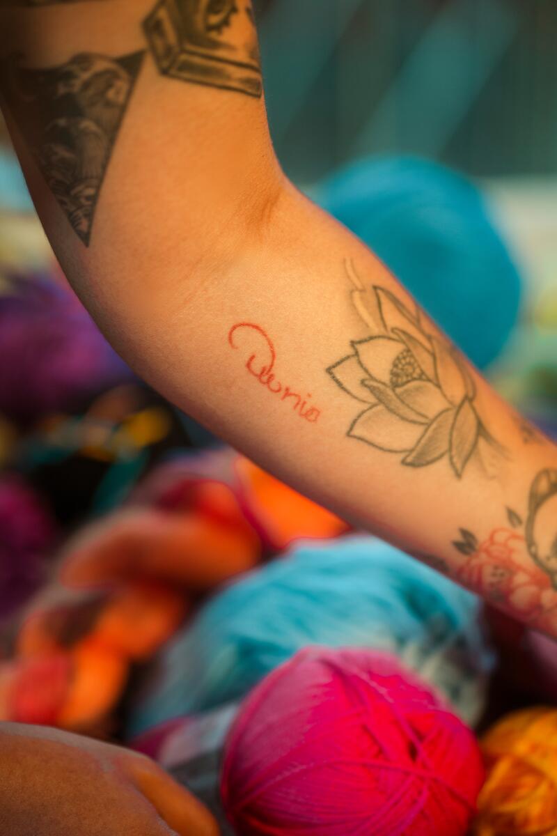 Grasso's arm with a tattoo of her mother's name, Dunia, in red next to a flower.