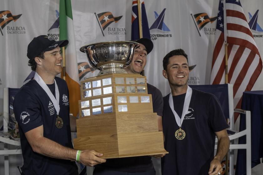 Cole Tapper of the Cruising Yacht Club of Australia, right, and crew members Jack Frewin and Hamish Vass raise the Governor's Cup on Saturday at the Balboa Yacht Club in Newport Beach.