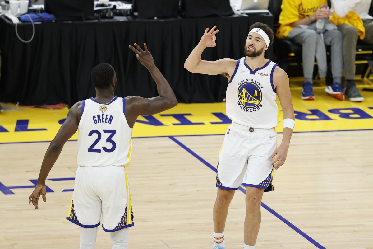 Warriors guard Klay Thompson celebrates with forward Draymond Green after making a three-point shot.