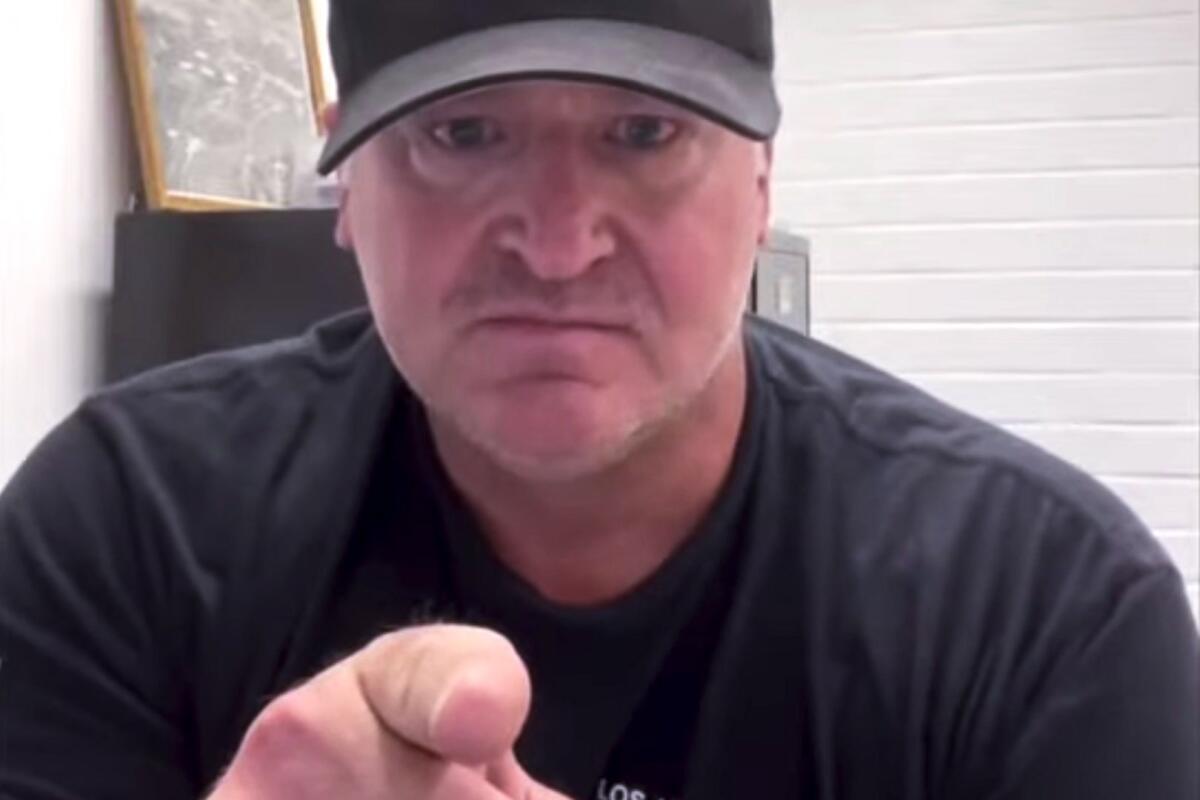 A man looks into a camera and points at it