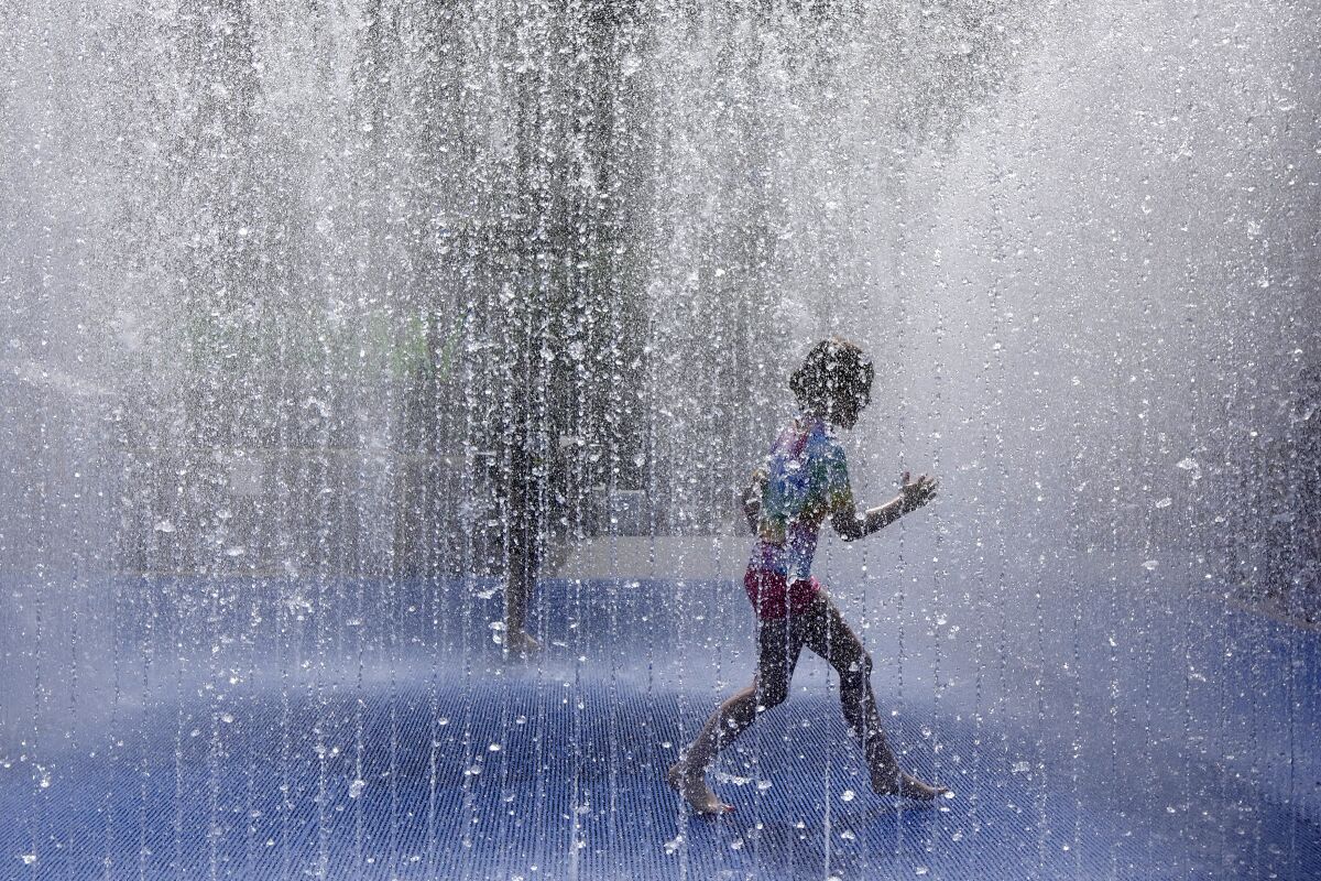 A child plays in a fountain in the warm weather in London