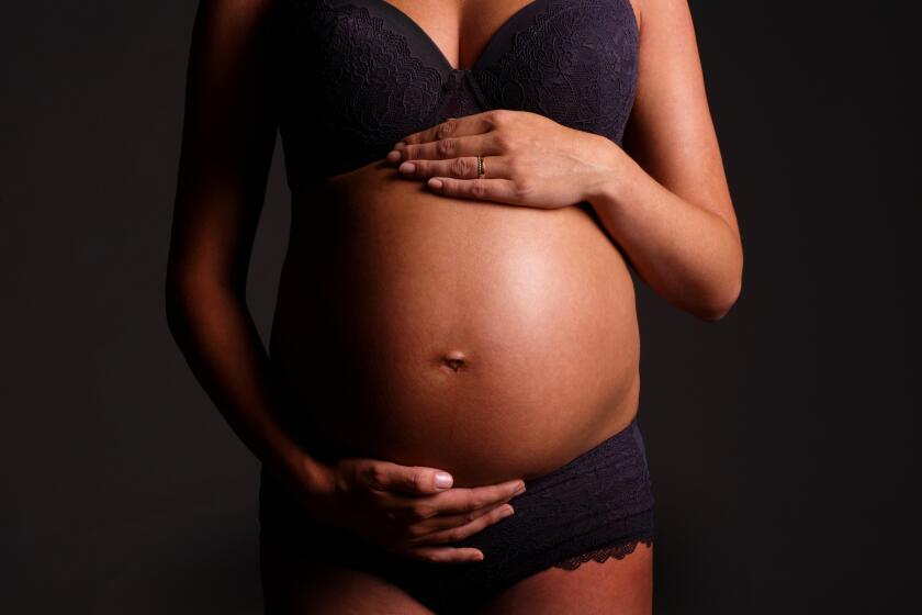 Close up of a pregnant lady's stomach, isolated - Hands on her stomach