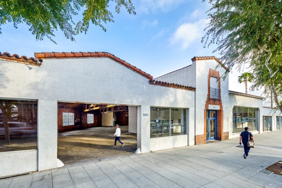 An architectural rendering shows a Spanish Revival-style storefront converted into a gallery space. 