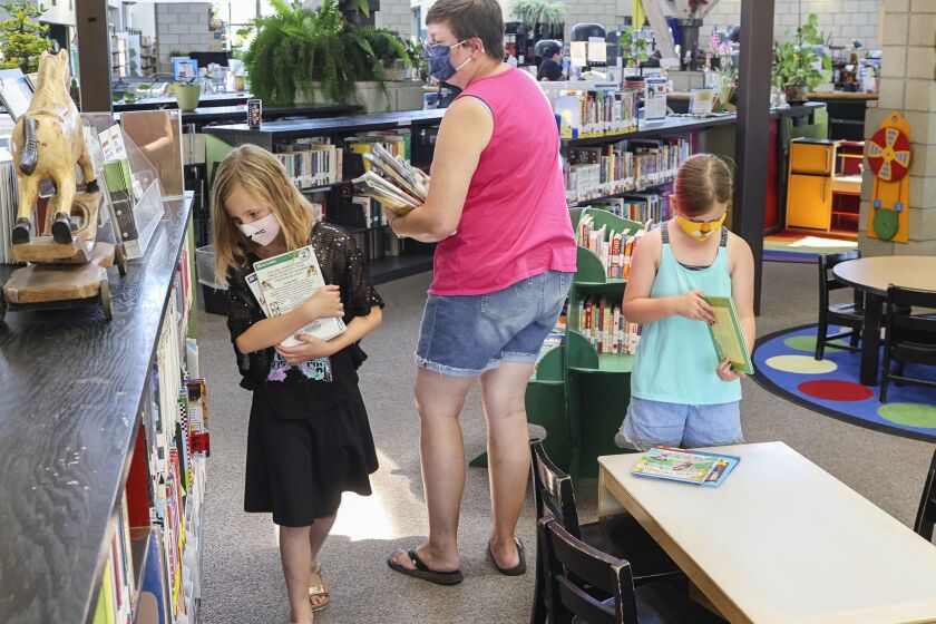 SAN DIEGO, CA - JULY 06: With San Diego Public Libraries resuming in-person services, (from left) Virginia VanGorder (left), 8, Tory VanGorder (mom), and Rowan VanGorder, 6, look for books at the newly reopened Linda Vista Library on Tuesday, July 6, 2021 in San Diego, CA. (Eduardo Contreras / The San Diego Union-Tribune)