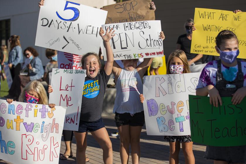 Students hold signs at a rally at the Huntington Beach City School District on Tuesday to protest the district's reopening plans.