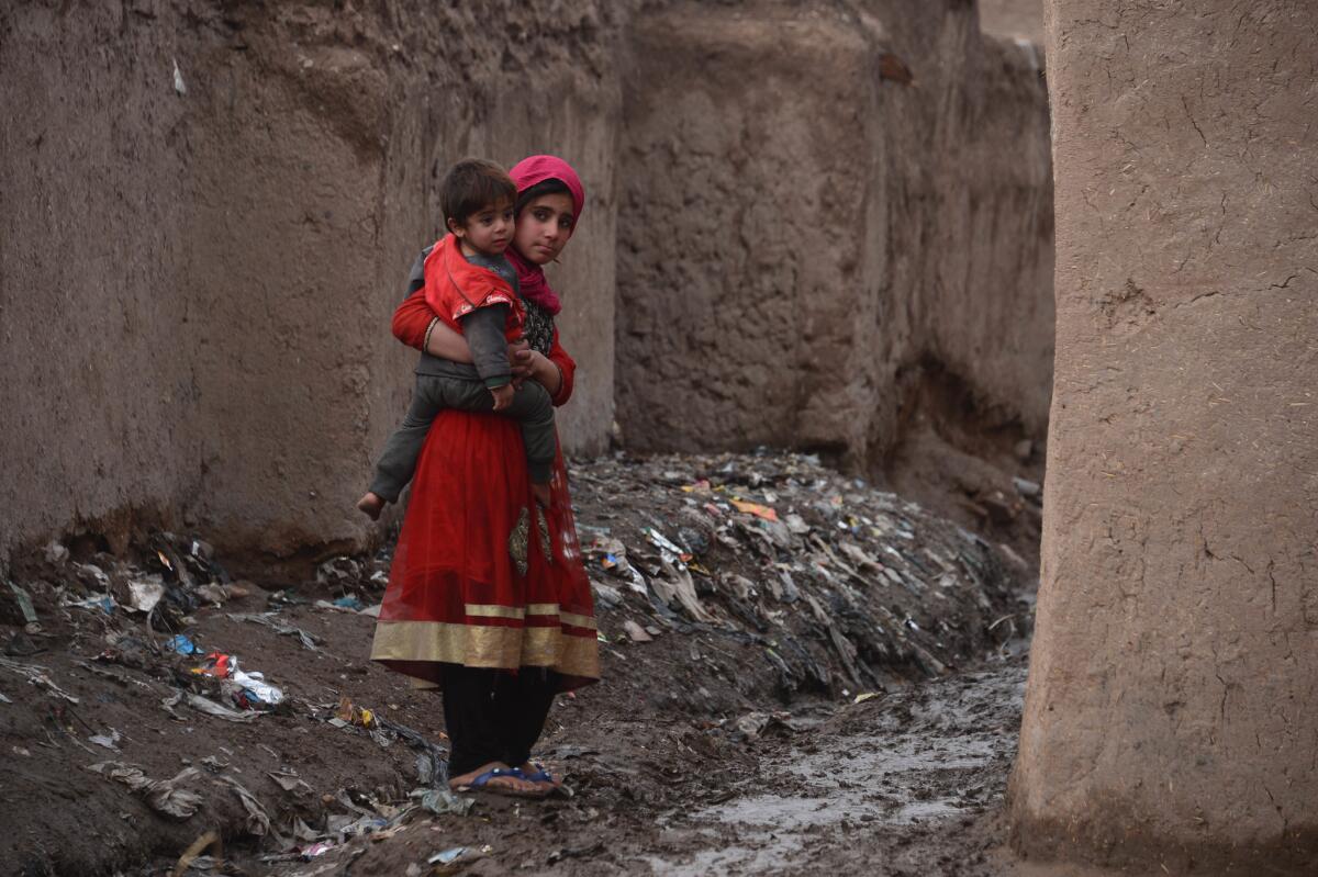 An Afghan girl holds her brother as she walks through a refugee camp in Herat on Jan. 23.