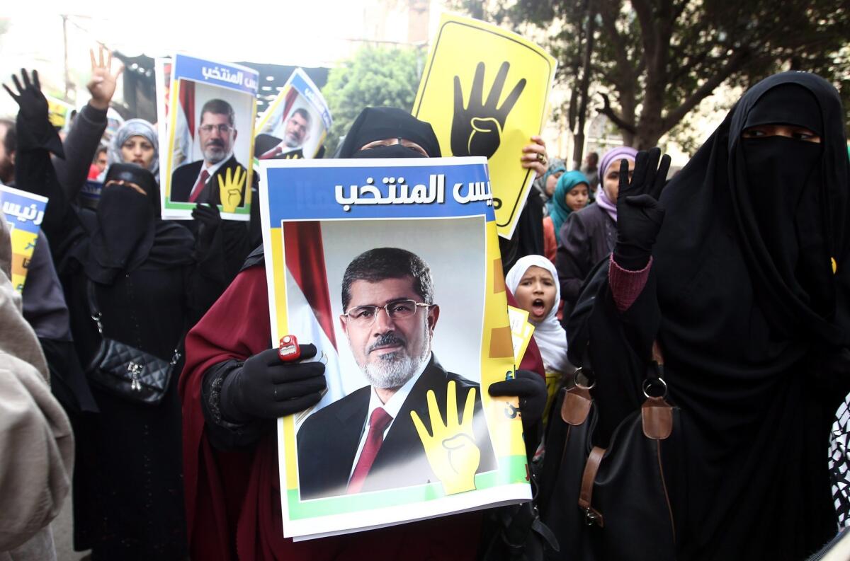 Egyptian supporters of ousted President Mohamed Morsi hold posters with photos depicting Morsi and the "four-fingered salute" during a protest in Cairo on Dec. 20, 2013.