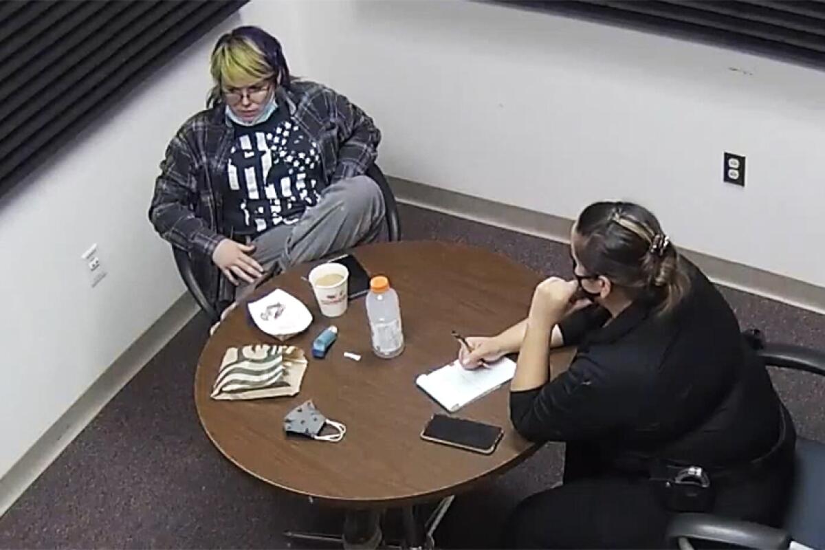 Hannah Gutierrez Reed, with green streaks in her hair, sits at a table with law enforcement.