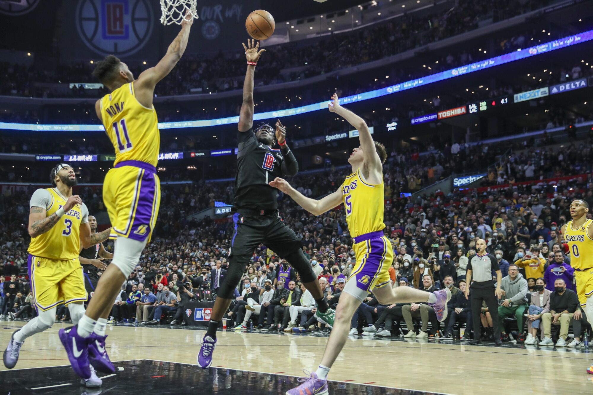 Clippers guard Reggie Jackson releases the game-winning shot over the Lakers' Malik Monk, left, and Austin Reaves.