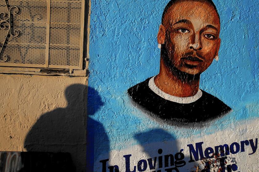 Passersby pause at a memorial to Ezell Ford, a mentally ill black man killed by police in South L.A. last year. The Los Angeles Police Department and its inspector general have said the shooting was justified, according to sources.