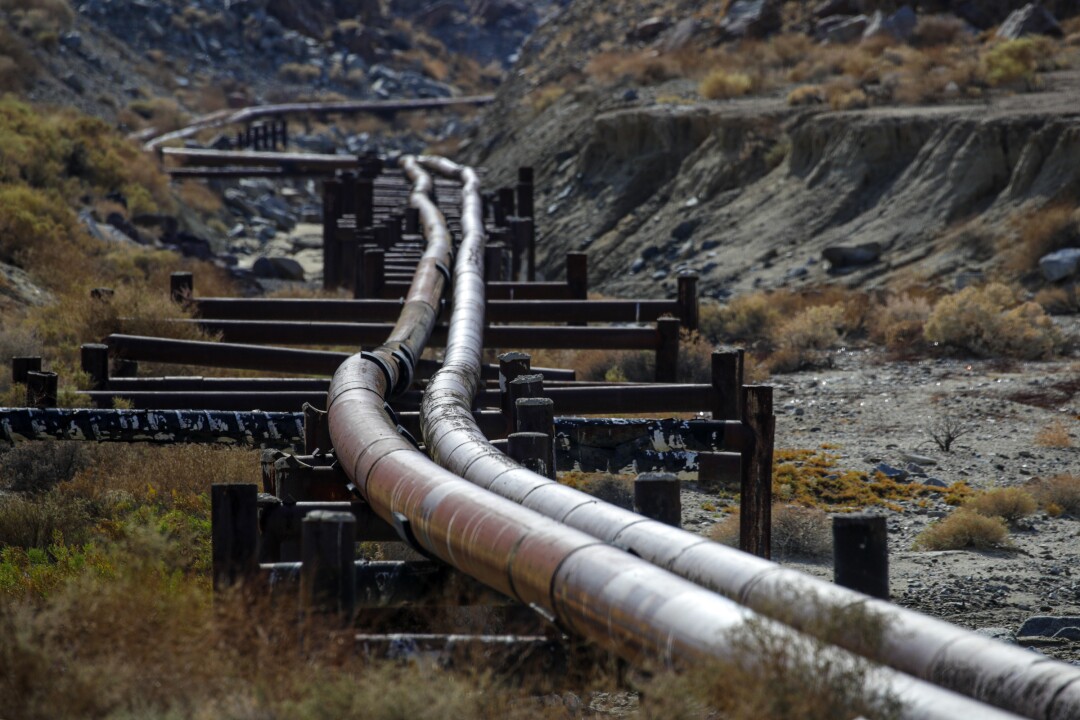 Two parallel above-ground water pipes run down a gully