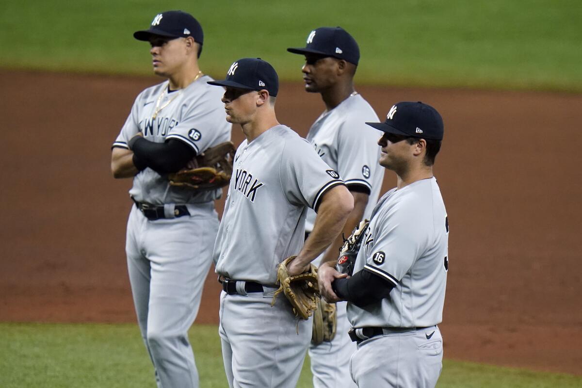 Jugadores de los Yanquis de Nueva York esperan a que el pitcher Michael King caliente 