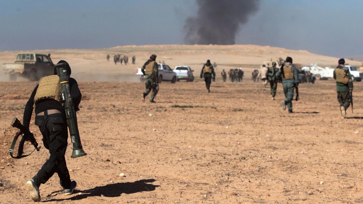 Smoke billows in the background as Iraqi forces, supported by the Hashed Shaabi (Popular Mobilization) paramilitaries, advance near the village of Husseinyah, south of Mosul, on Feb. 20, 2017.