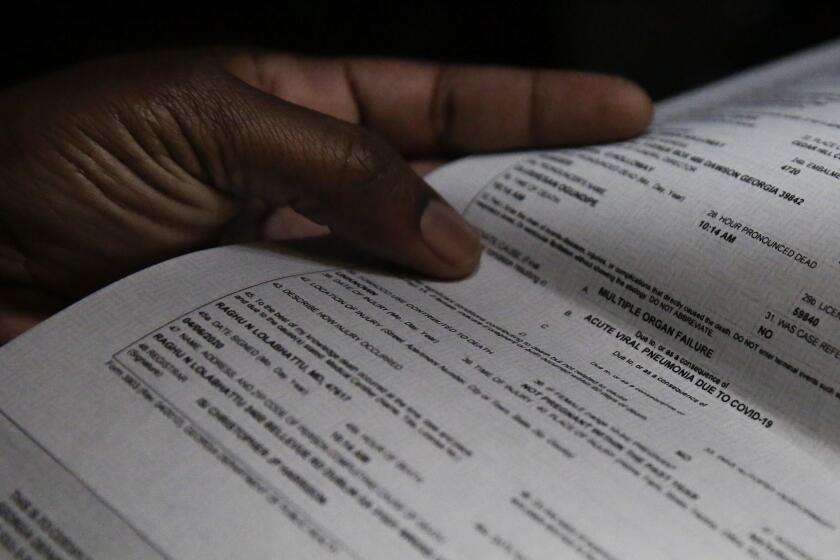 Latasha Taylor points to a death certificate showing the cause of death being acute viral pneumonia due to COVID-19