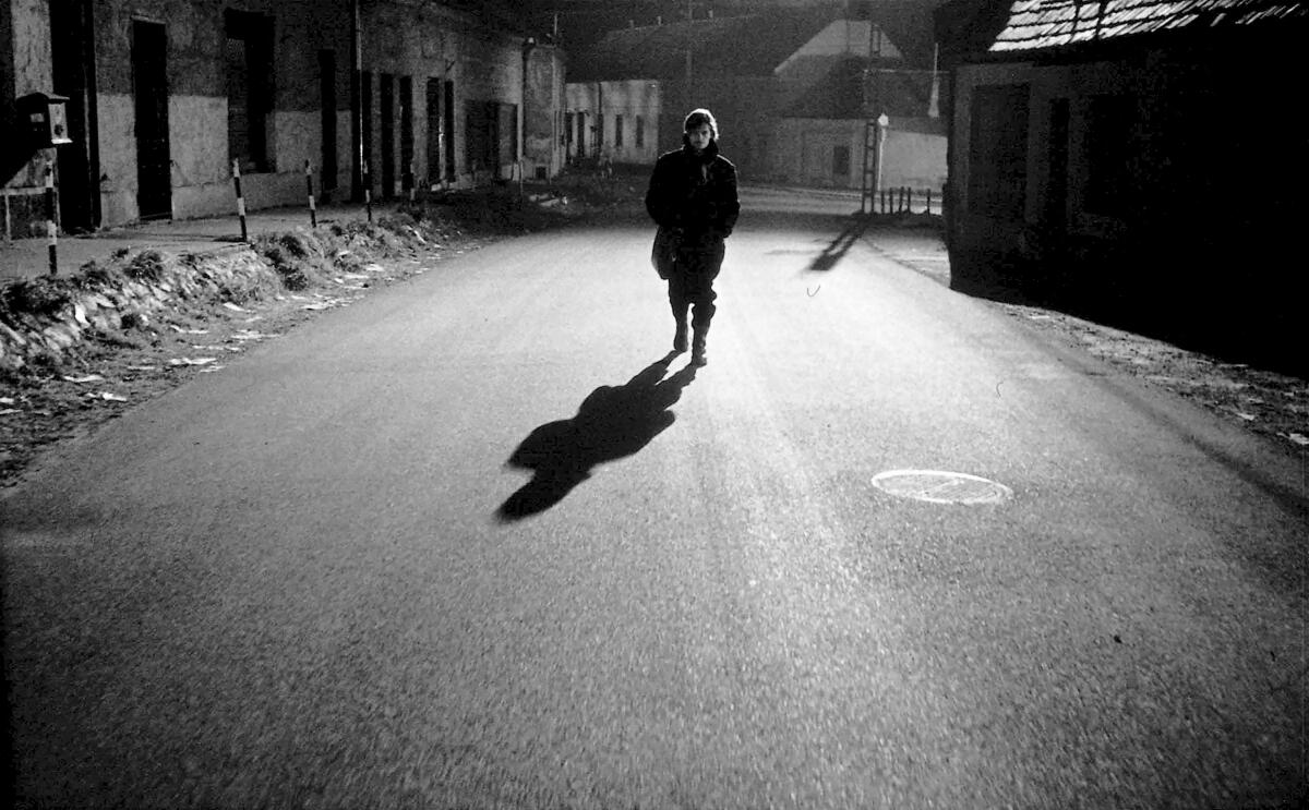 A lonely man walks down an empty street at night.