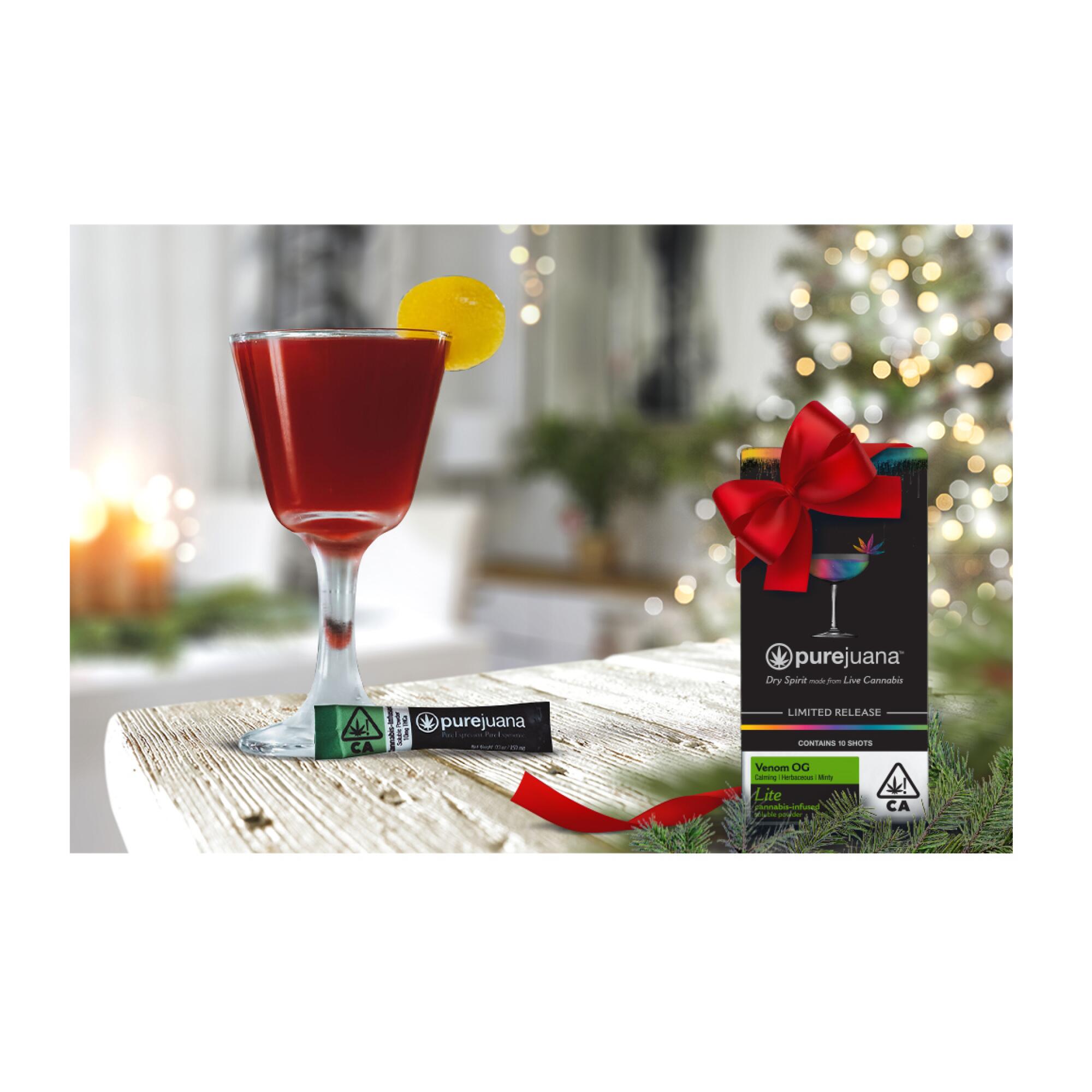 A glass filled with red liquid and a box with a bow against a holiday backdrop.