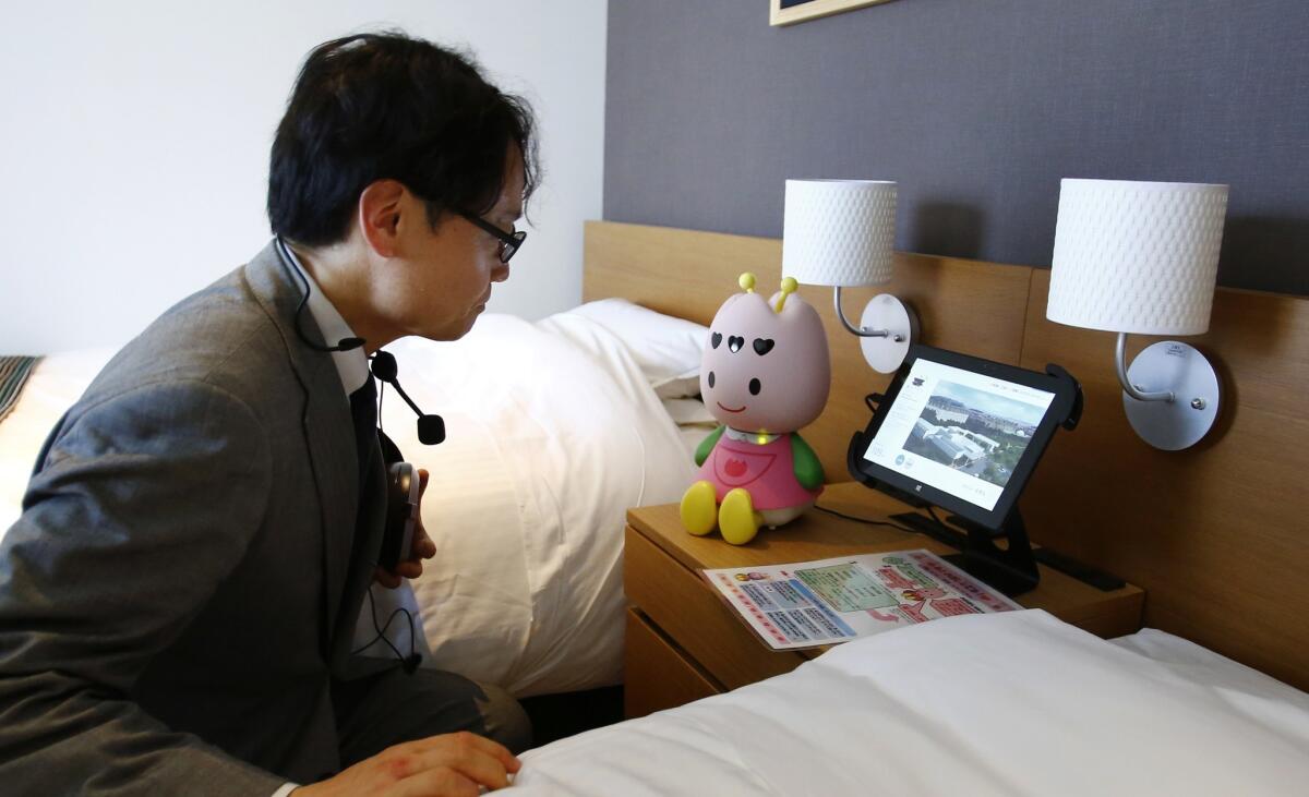 A hotel employee talks to concierge robot Tuly at the new robot hotel, aptly called Henn na Hotel or Weird Hotel, in Sasebo, southwestern Japan, Wednesday, July 15, 2015. From the receptionist that does the check-in and check-out to the porter thatís a stand-on-wheels taking luggage up to the room, the hotel, that is run as part of Huis Ten Bosch amusement park, is ìmannedî almost totally by robots to save labor costs. (AP Photo/Shizuo Kambayashi)