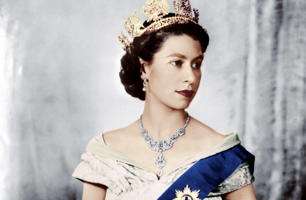 A formal portrait of a queen with sash, fan, elaborate jewelry and crown.